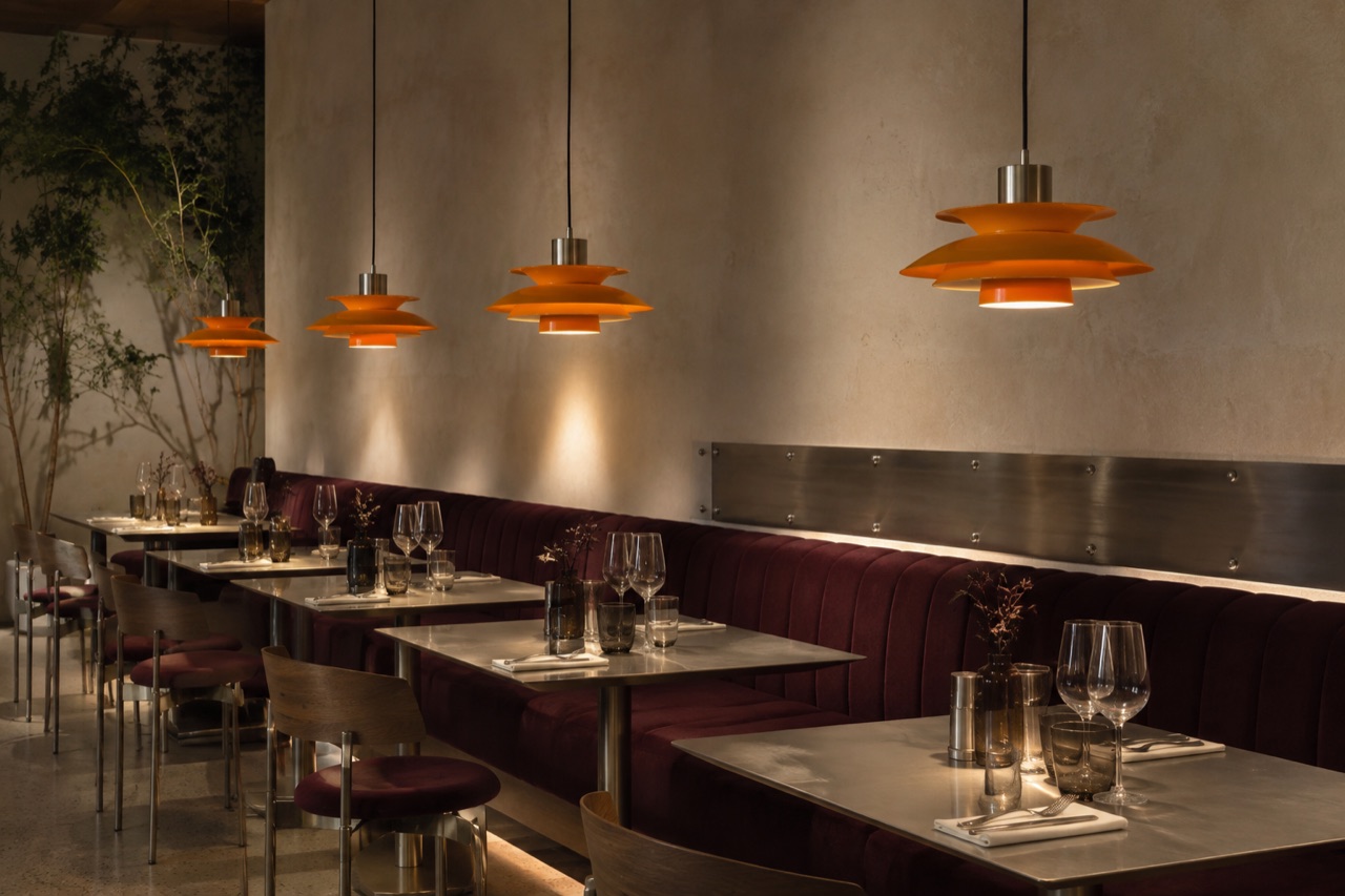 Illustrert restaurant med varme oransje pendlar og mørk raud sitjebenk