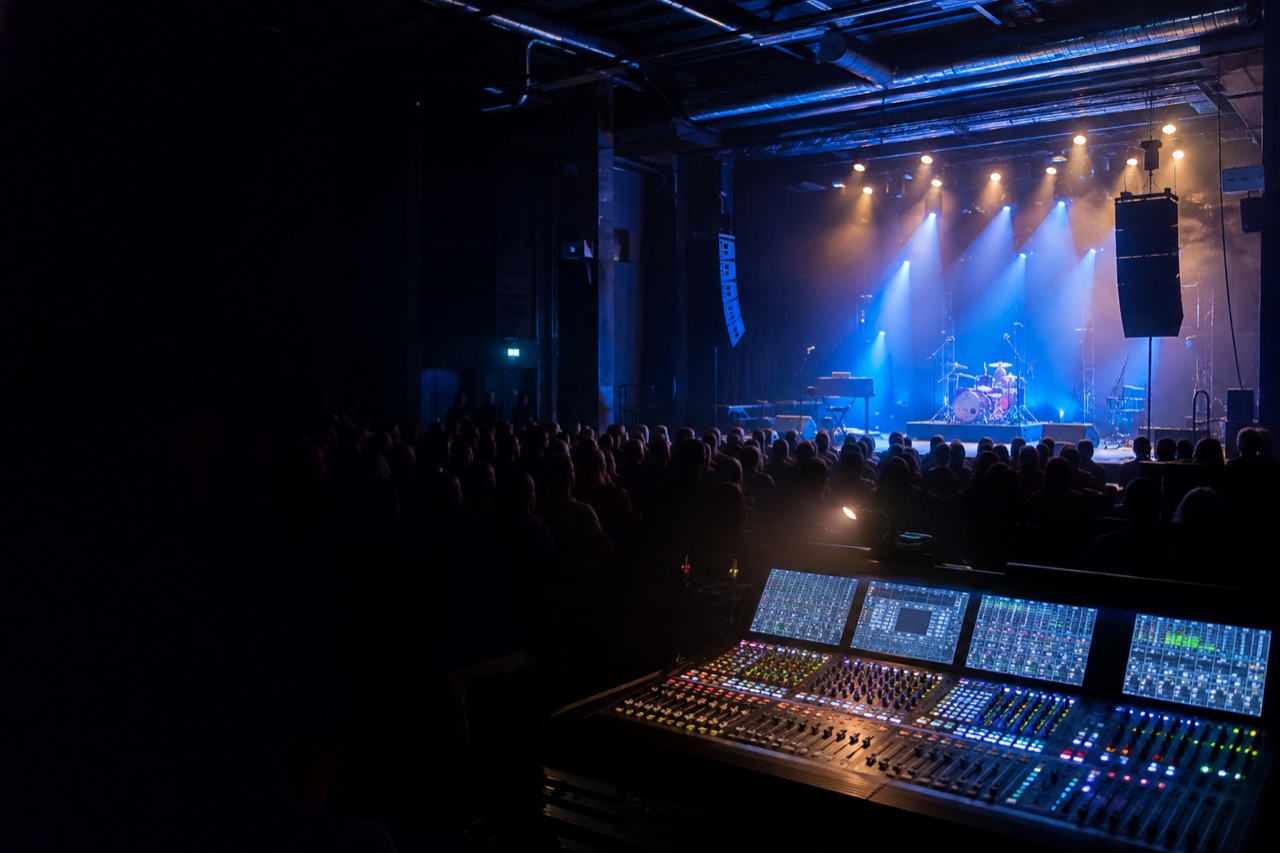 KI-laga konsertillustrasjon med miksepult, scene og publikum